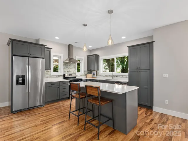 a kitchen with stainless steel appliances granite countertop a refrigerator a sink dishwasher a stove with wooden cabinets and wooden floor