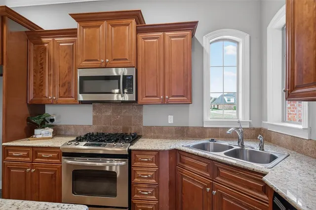 a kitchen with granite countertop a sink a stove and microwave