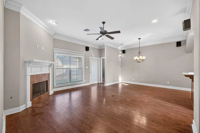 an empty room with wooden floor fireplace and windows