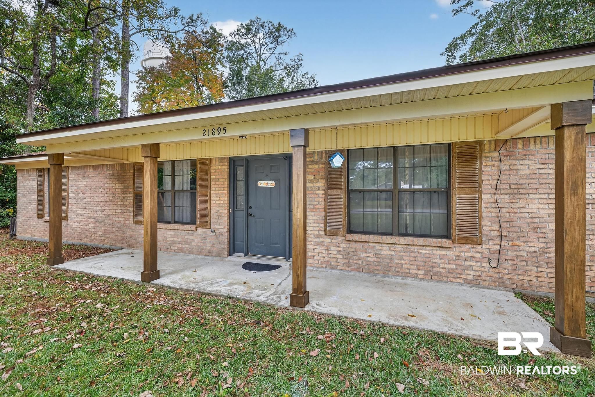 21895 2nd Street Silverhill, AL 36576 - Photo 4 of 43 View of exterior entry with brick siding, a yard, and a porch