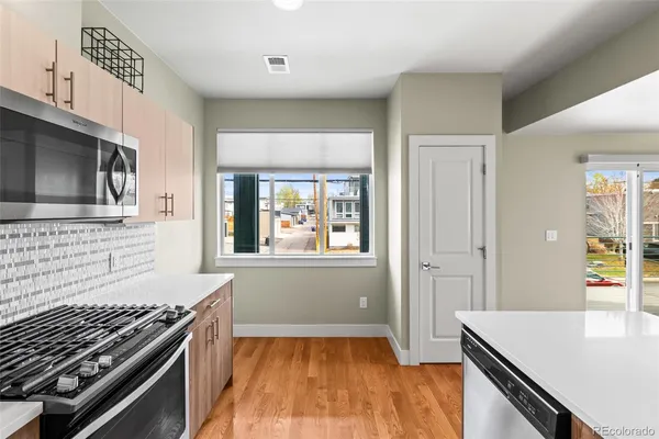 a kitchen with stainless steel appliances a stove a sink a refrigerator white cabinets and wooden floor