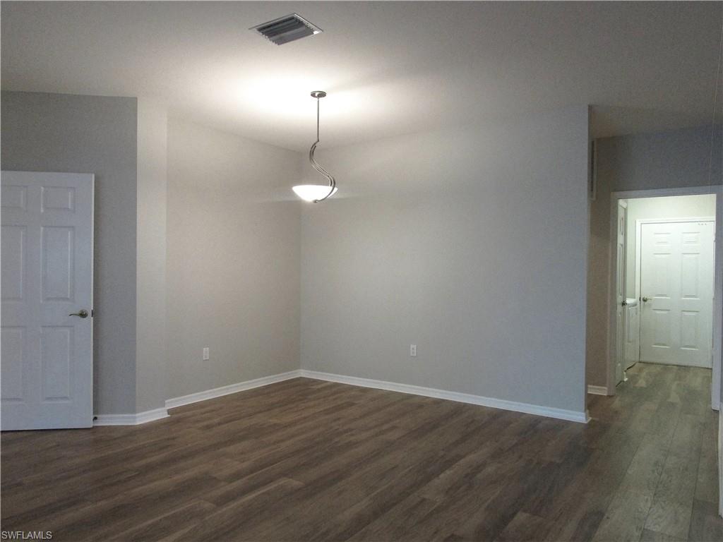 7005 Pinnacle Lane, Unit 1501 Naples, FL 34110 - Photo 6 of 45 an empty room with wooden floor and mirror