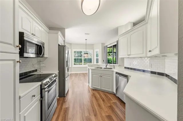 a kitchen with granite countertop a stove top oven a sink dishwasher and white cabinets with wooden floor