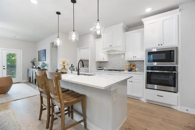 a kitchen with stainless steel appliances kitchen island granite countertop a table chairs and a sink