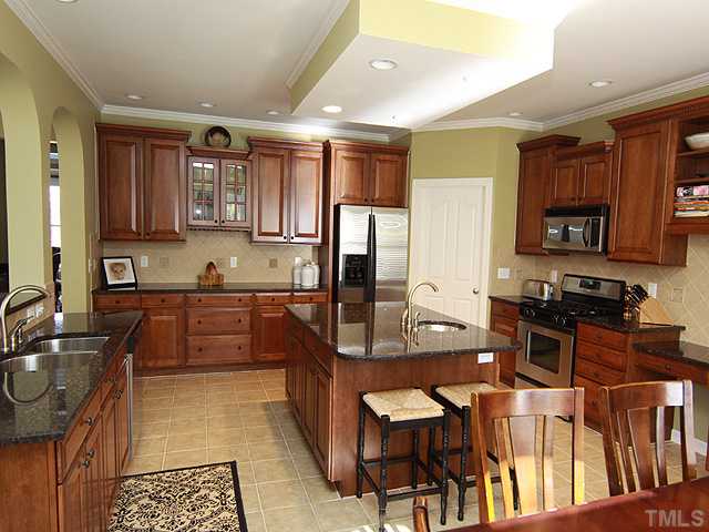 8232 Clarks Branch Drive Raleigh, NC 27613 - Photo 2 of 11 a kitchen with stainless steel appliances granite countertop a stove top oven a sink a dining table and chairs
