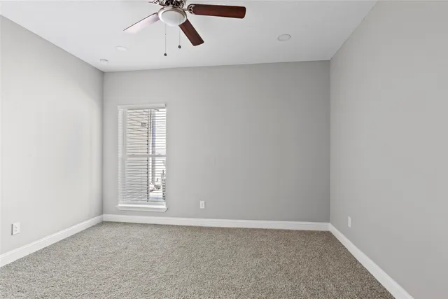 an empty room with a window and a ceiling fan