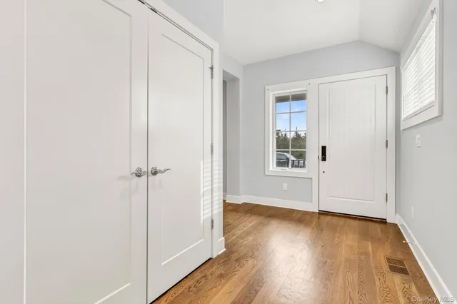an empty room with wooden floor closet and windows
