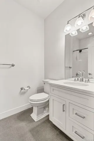 a bathroom with a granite countertop toilet sink and mirror