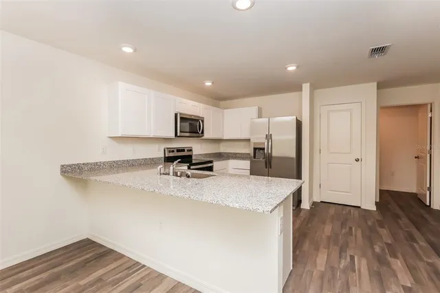 a kitchen with a refrigerator a sink and wooden floor
