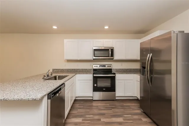 a kitchen with a sink a refrigerator and a stove top oven with wooden floor