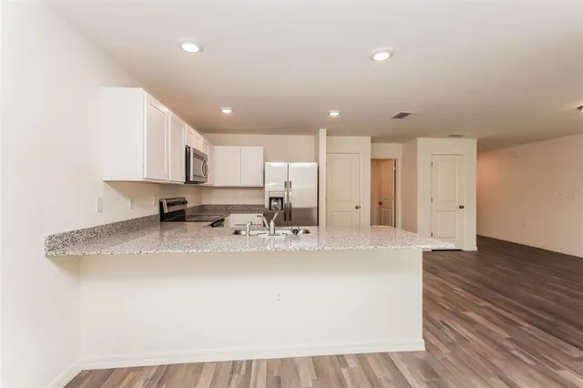 a large white kitchen with kitchen island a sink stainless steel appliances and cabinets