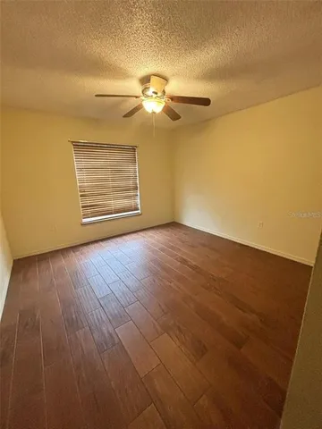 a view of empty room with wooden floor and fan