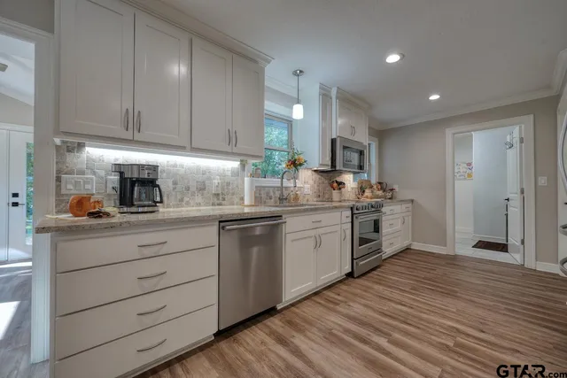 a kitchen with granite countertop wooden floors stainless steel appliances and cabinets