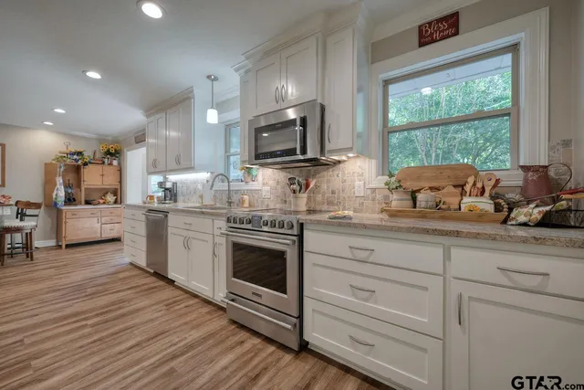 a kitchen with stainless steel appliances white cabinets a sink and a stove