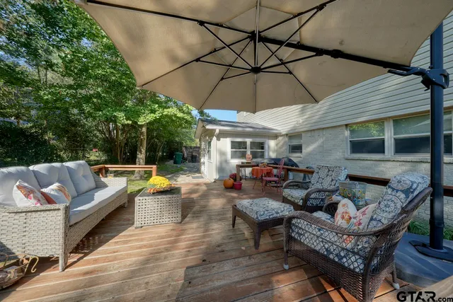 a view of a roof deck with table and chairs under an umbrella with wooden floor