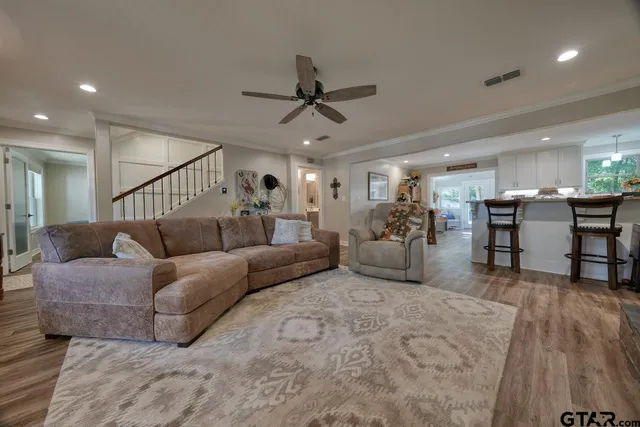 a living room with furniture kitchen view and a wooden floor