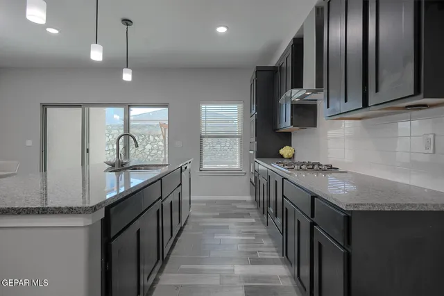 a kitchen with stainless steel appliances granite countertop a sink a oven a refrigerator cabinets and wooden floor