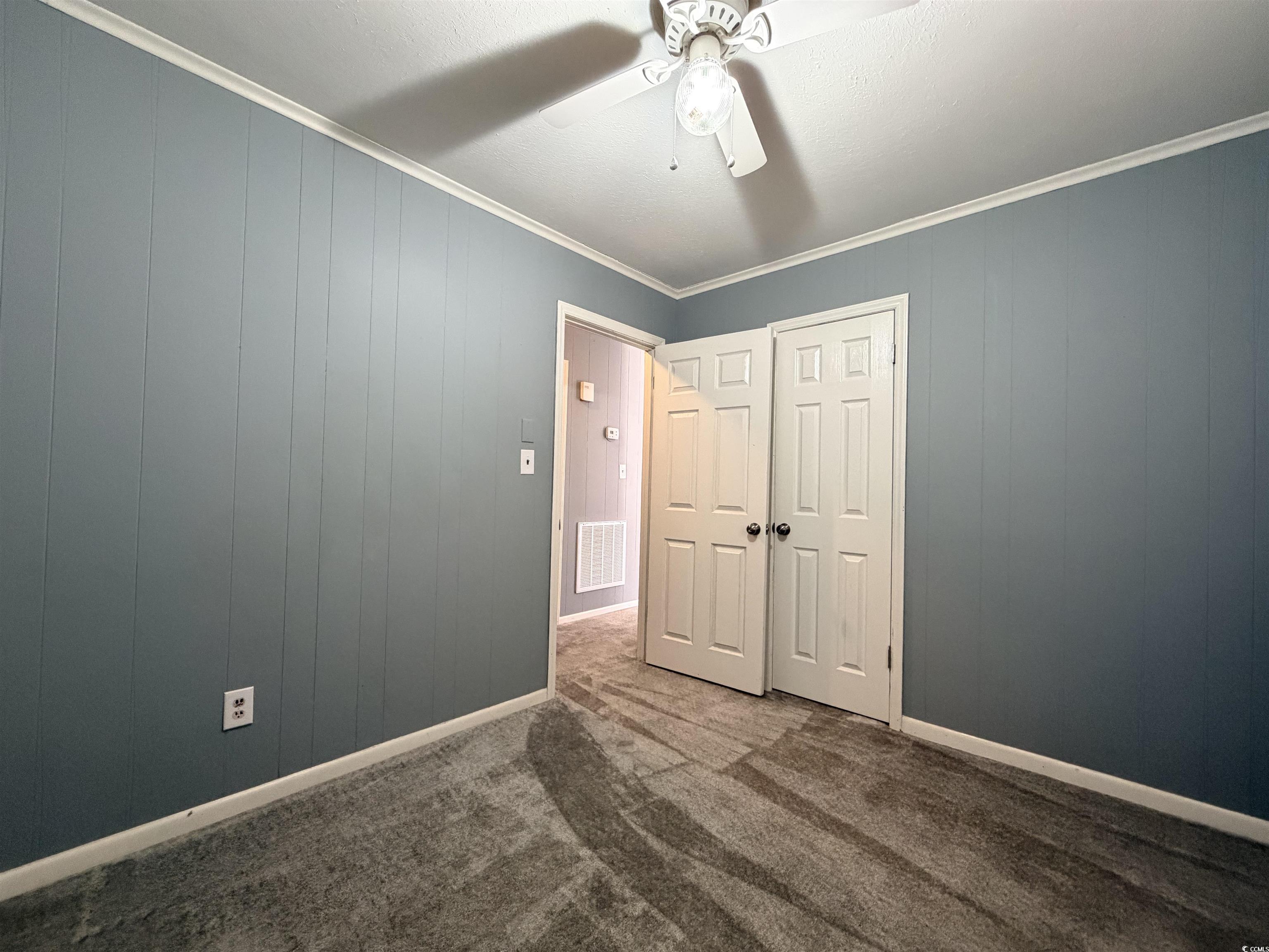 107 Aster Drive Greer, SC 29651 - Photo 15 of 20 Unfurnished bedroom with ornamental molding, dark carpet, a ceiling fan, and wooden walls