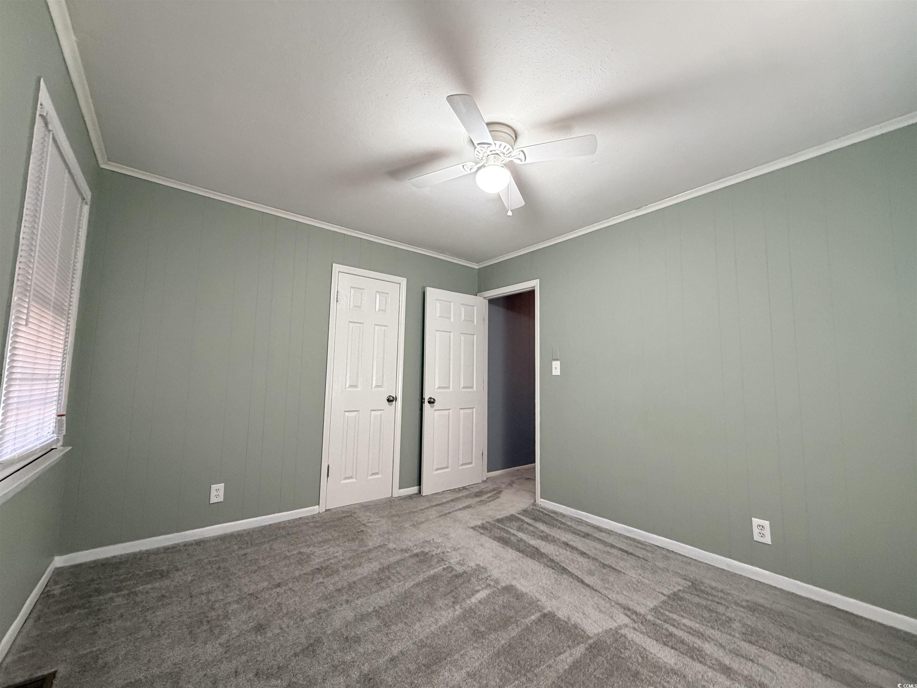 107 Aster Drive Greer, SC 29651 - Photo 16 of 20 Unfurnished bedroom with crown molding, carpet flooring, wood walls, and a ceiling fan