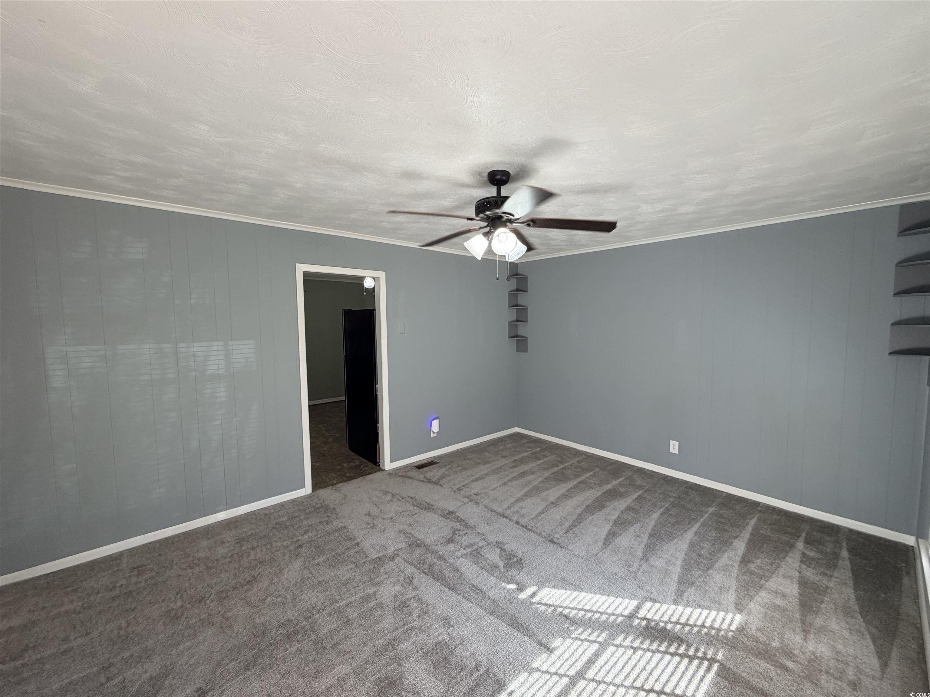 107 Aster Drive Greer, SC 29651 - Photo 17 of 20 Unfurnished room featuring wood walls, ornamental molding, carpet floors, and a ceiling fan