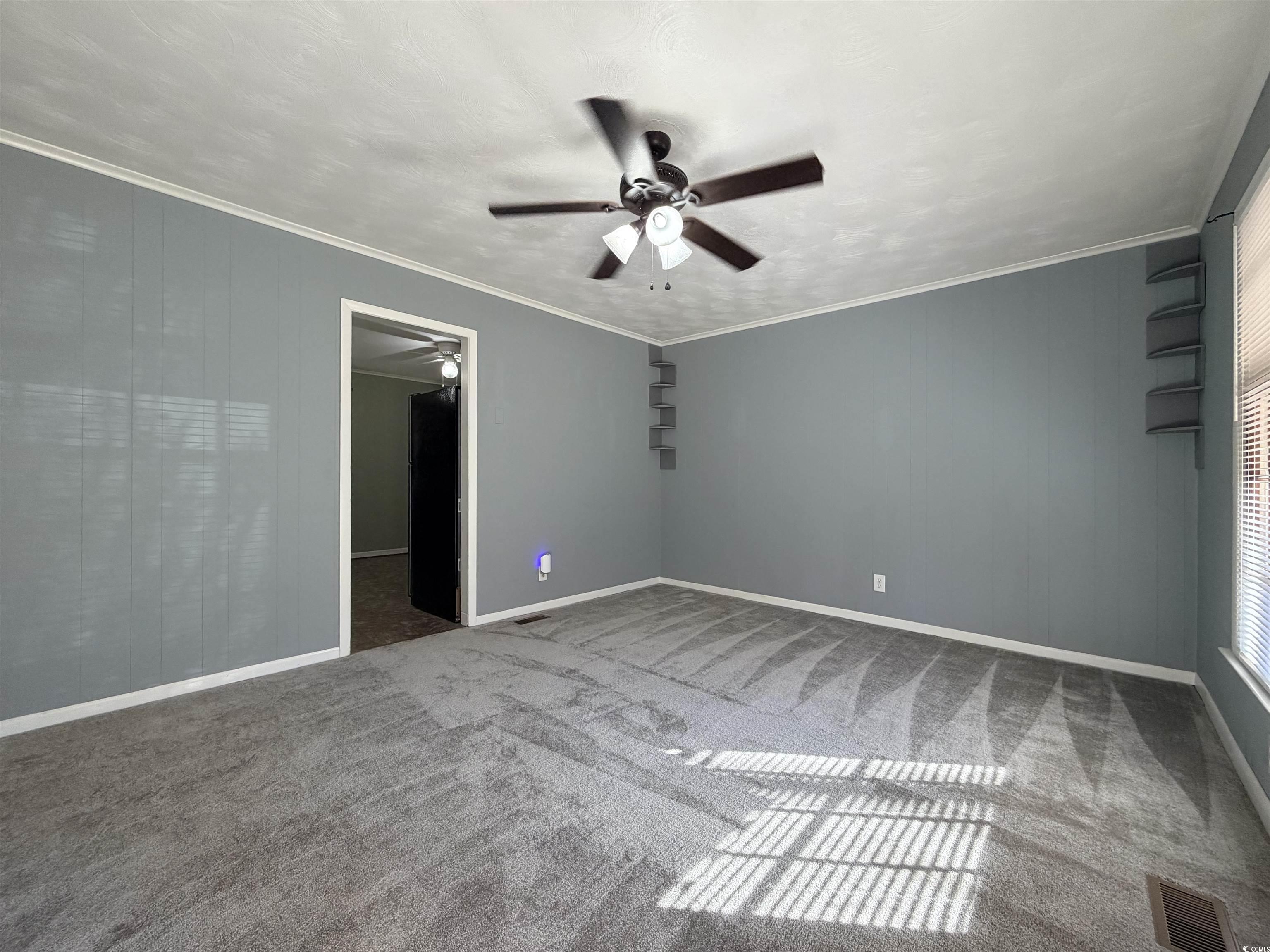 107 Aster Drive Greer, SC 29651 - Photo 3 of 20 Empty room featuring crown molding, a ceiling fan, wooden walls, and light colored carpet