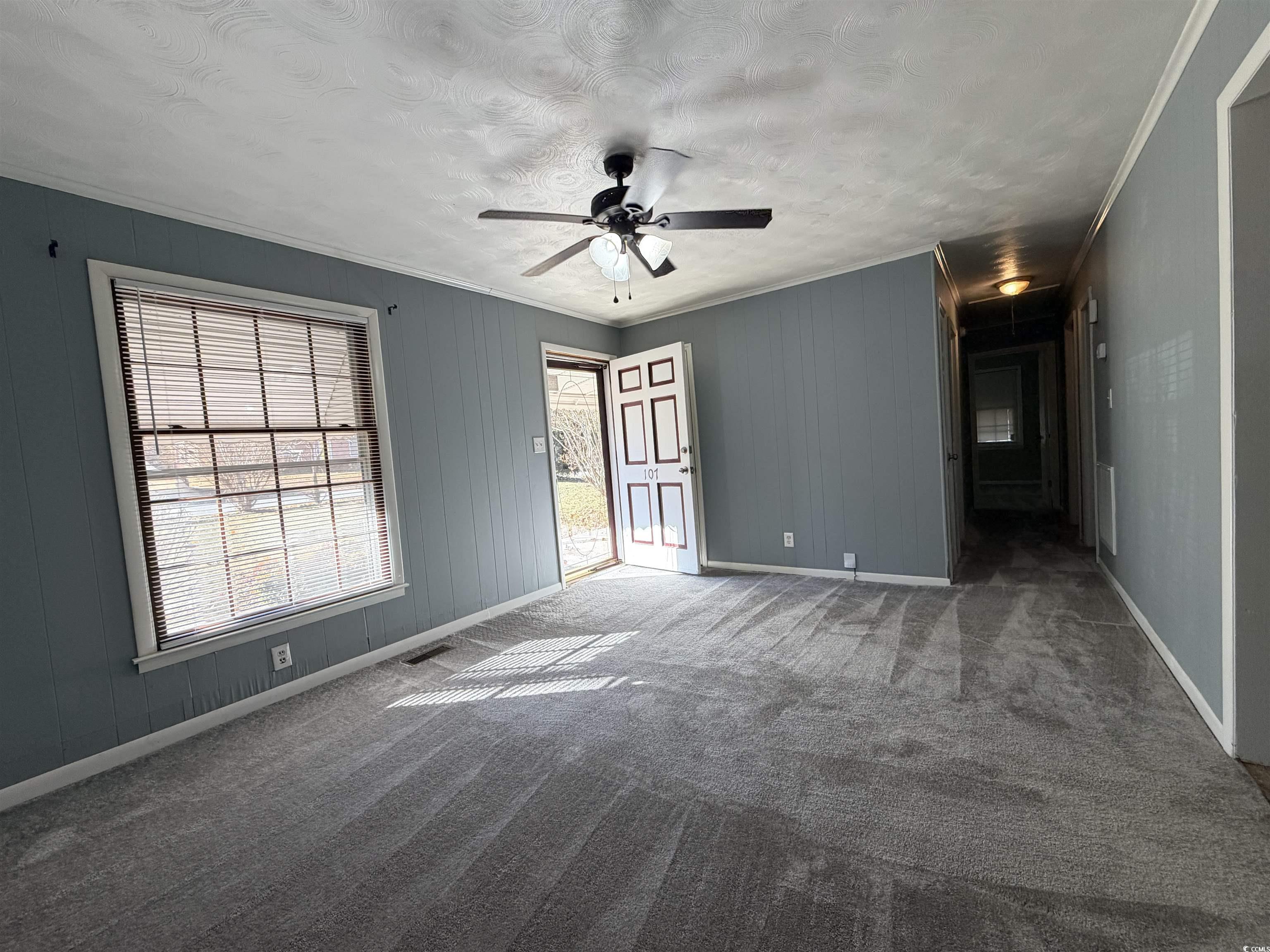 107 Aster Drive Greer, SC 29651 - Photo 4 of 20 Spare room with carpet, crown molding, a textured ceiling, a ceiling fan, and wood walls