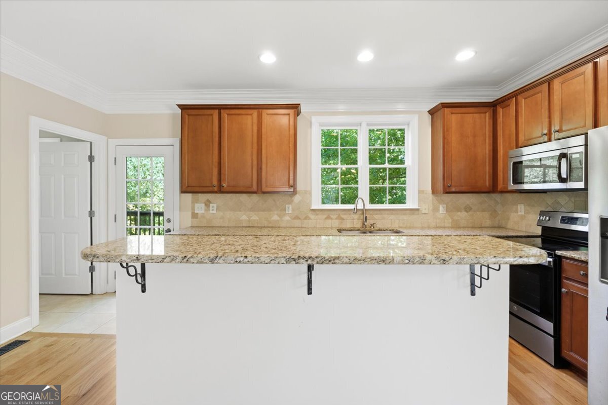 728 Markhams Drive Madison, GA 30650 - Photo 16 of 51 a kitchen with granite countertop wooden cabinets a sink a window and stainless steel appliances
