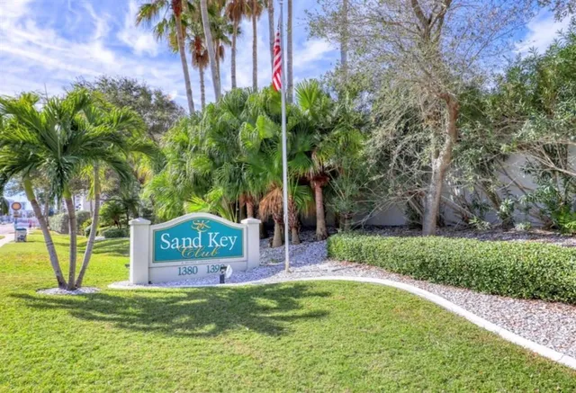 a sign that is sitting in front of a big yard with potted plants