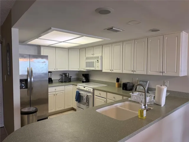 a kitchen with stainless steel appliances granite countertop a sink refrigerator stove and white cabinets
