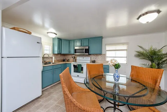 a kitchen with stainless steel appliances granite countertop a refrigerator a stove a sink dishwasher and a dining table with wooden floor