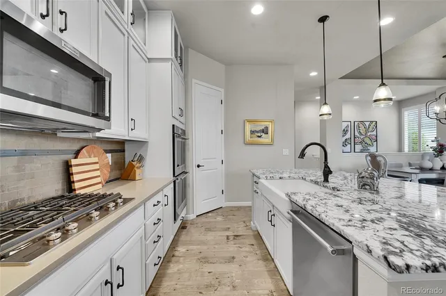 a large kitchen with stainless steel appliances granite countertop a stove a sink and a microwave