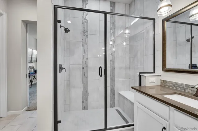 a bathroom with a granite countertop shower sink and mirror