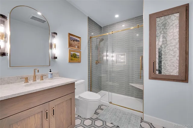 a bathroom with a double vanity sink toilet mirror and shower