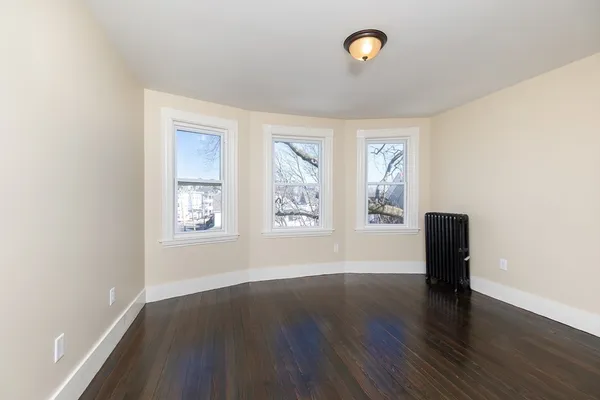 a view of an empty room with window and wooden floor