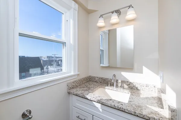 a bathroom with a granite countertop sink and a mirror