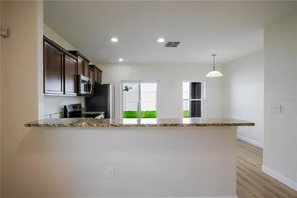 a kitchen with granite countertop a refrigerator stove top oven and sink