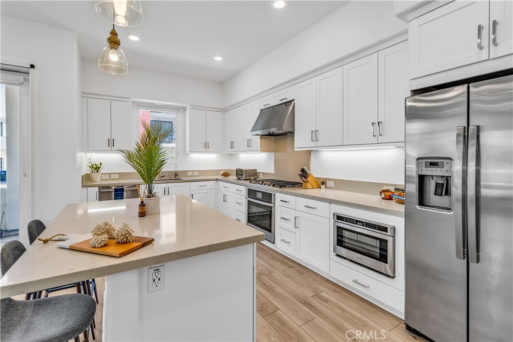 202 Waypoint Tustin, CA 92782 - Photo 13 of 46 a kitchen with stainless steel appliances a white table chairs and a refrigerator
