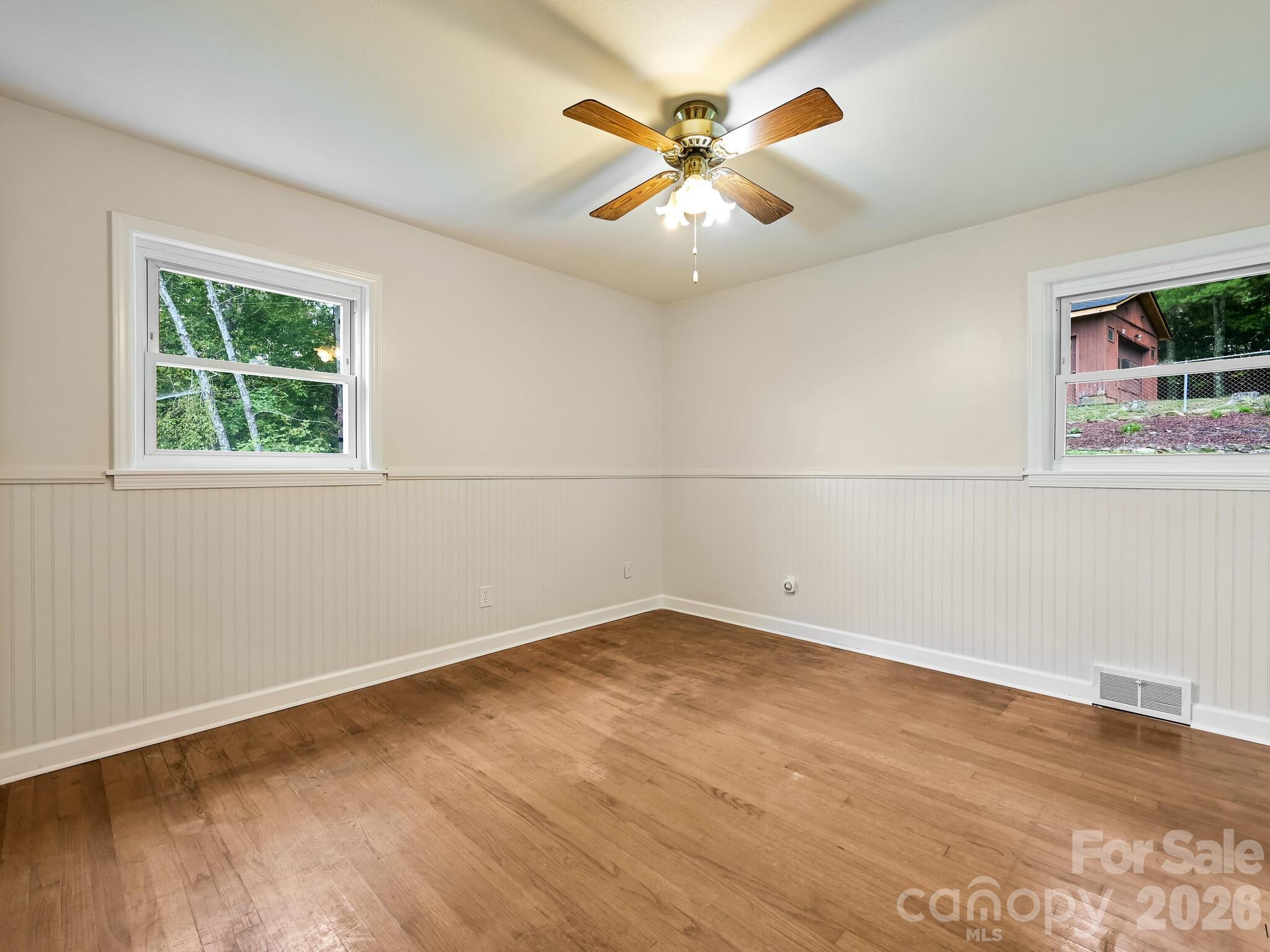 651 Case Cove Road Candler, NC 28715 - Photo 11 of 45 an empty room with wooden floor and windows