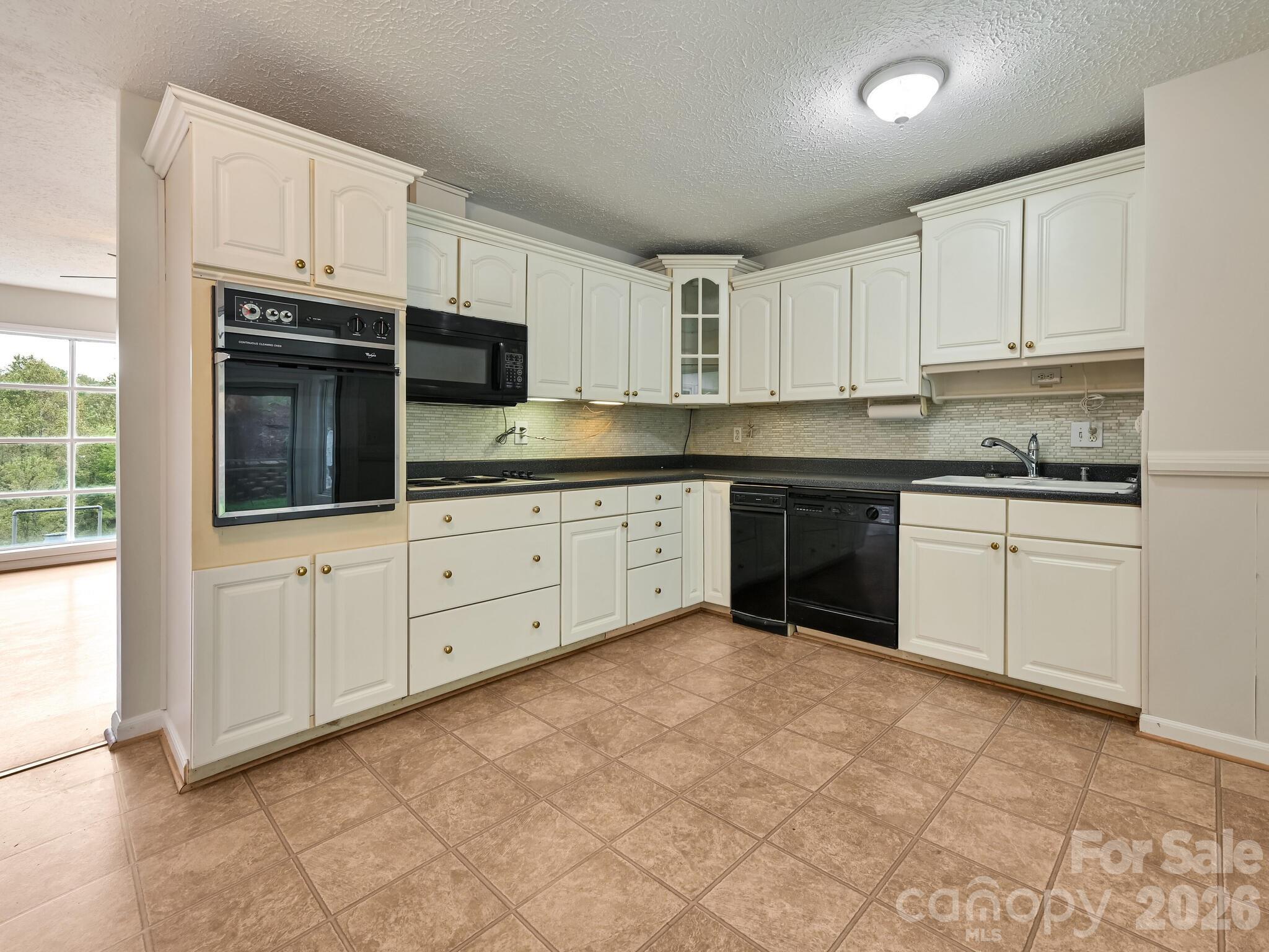 651 Case Cove Road Candler, NC 28715 - Photo 7 of 45 a kitchen with granite countertop white cabinets and white appliances