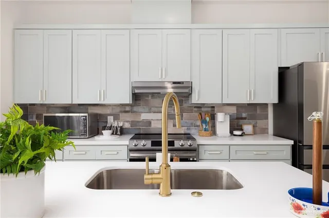 a kitchen with stainless steel appliances kitchen island granite countertop a sink a stove and cabinets