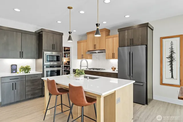 a kitchen with granite countertop a refrigerator a stove a kitchen island and chairs with wooden floor