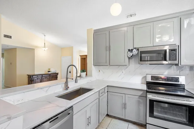 a kitchen with stainless steel appliances granite countertop a stove a sink and a microwave