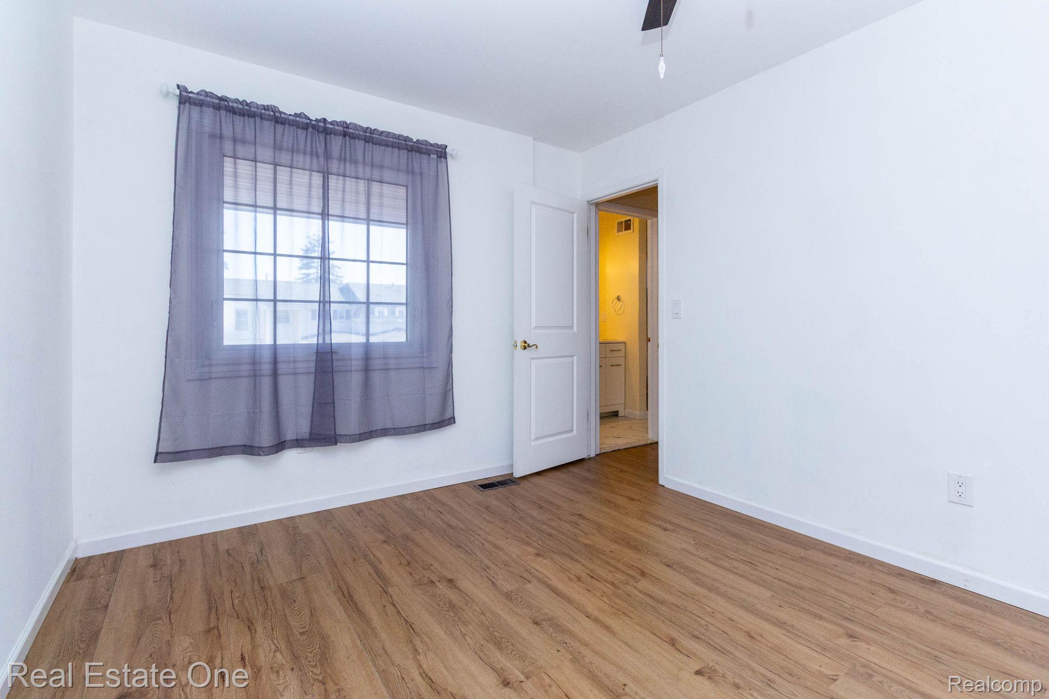 111 Manor Way Rochester, MI 48309 - Photo 22 of 36 Spacious room featuring wood-finish flooring, white baseboards, and a multi-pane window with sheer curtains
