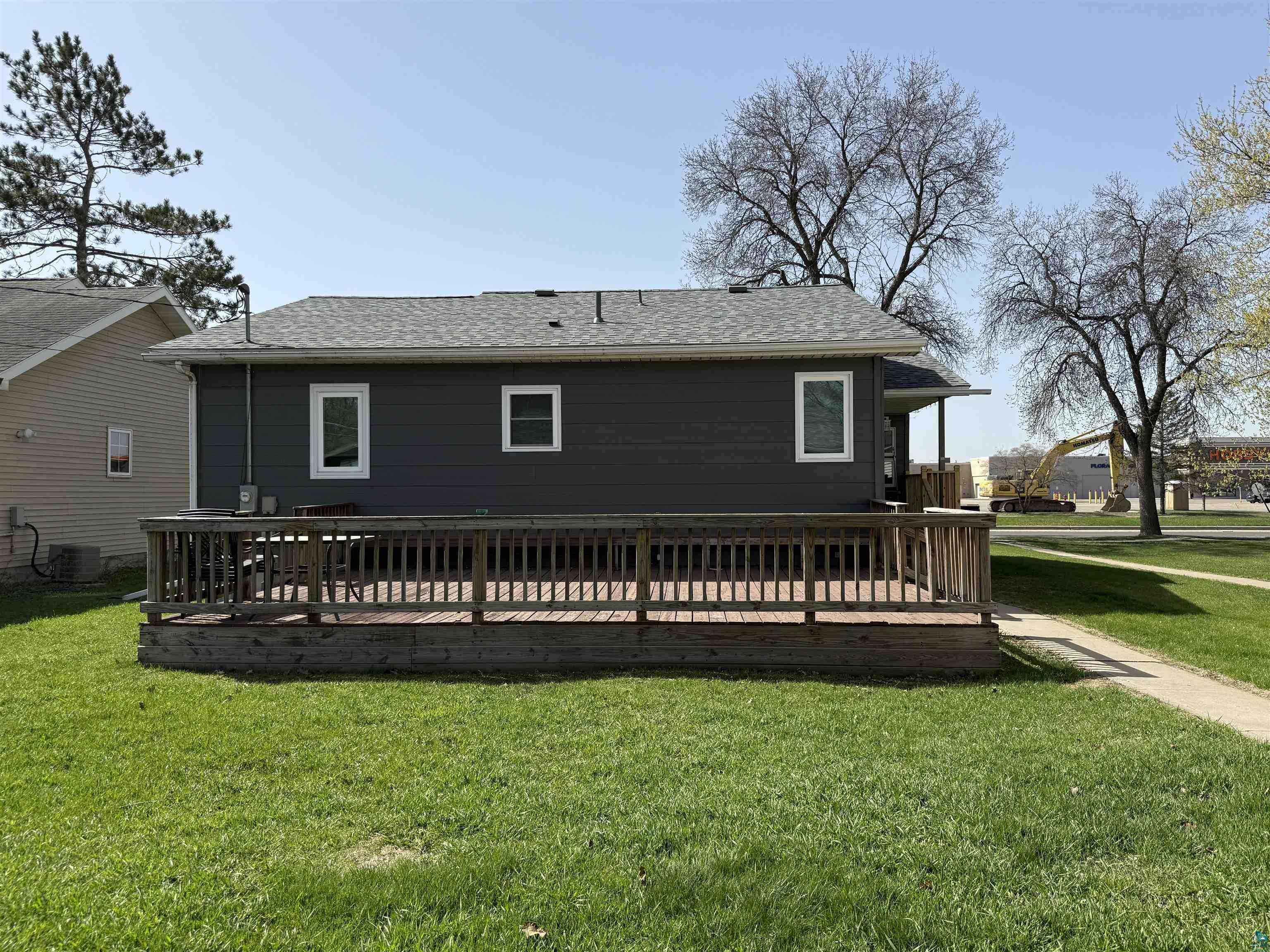 1321 South 13th Street Virginia, MN 55792 - Photo 28 of 33 Expansive rear deck with wooden railings, featuring a dark gray siding exterior and white-framed windows