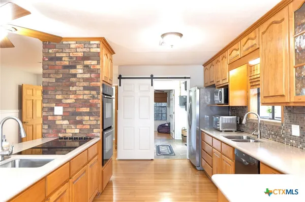 a large kitchen with kitchen island a large window a sink and stainless steel appliances