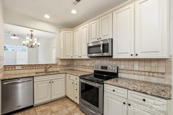 a kitchen with stainless steel appliances granite countertop white cabinets a sink and dishwasher