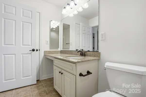 a bathroom with a granite countertop sink a toilet and a mirror