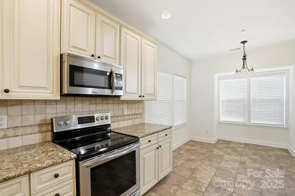a kitchen with stainless steel appliances granite countertop white cabinets granite counter tops and a window