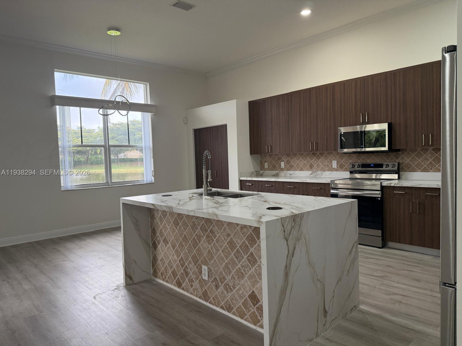 2408 Deer Creek Road Weston, FL 33327 - Photo 8 of 30 a kitchen with kitchen island a sink wooden floor and a stove top oven