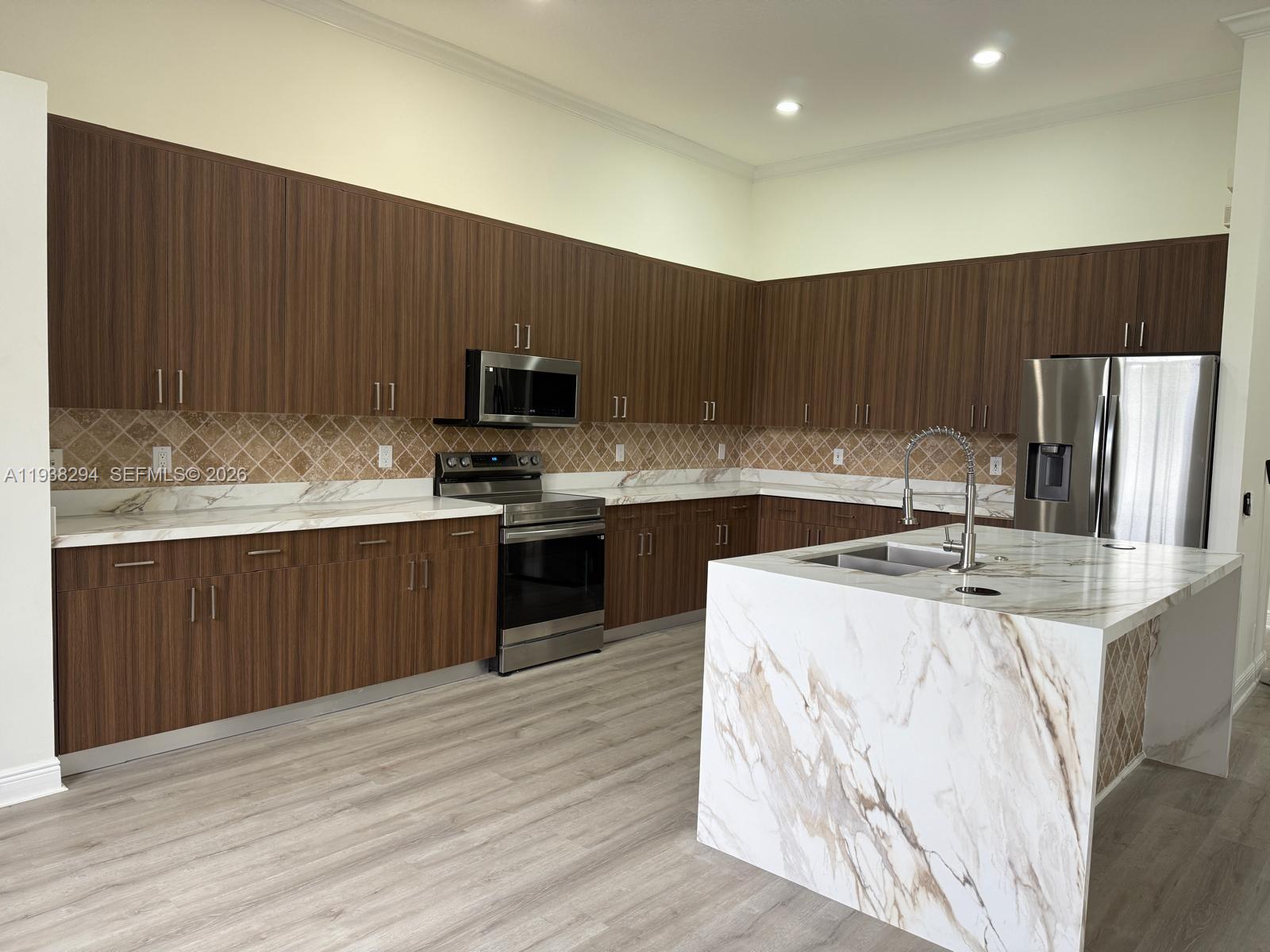 2408 Deer Creek Road Weston, FL 33327 - Photo 9 of 30 a kitchen with kitchen island a stove a sink a refrigerator and cabinets